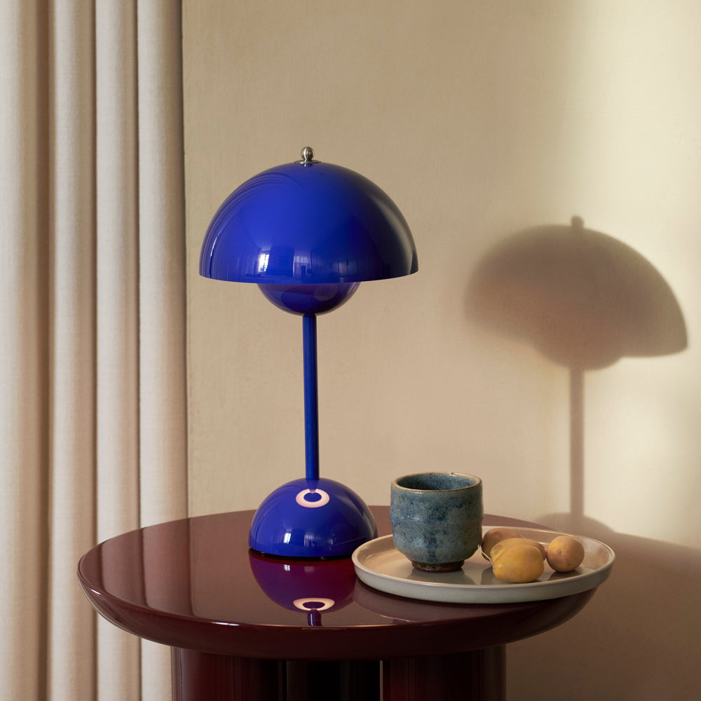 Lamp on side table next to platter with cup.