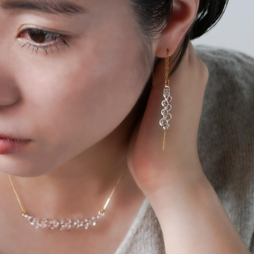 Close-up view model wearing earrings and necklace.
