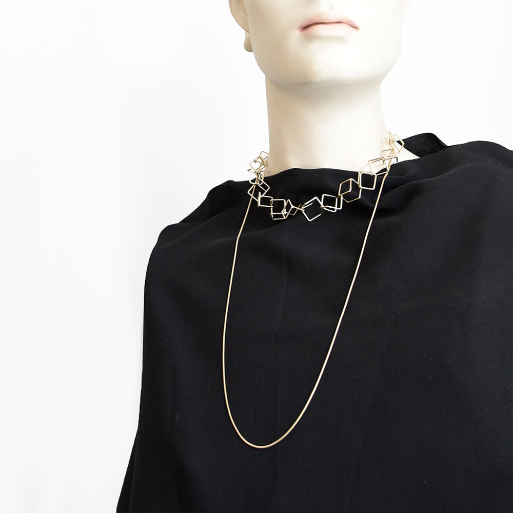 Styled view of looped gold necklace on black fabric. 