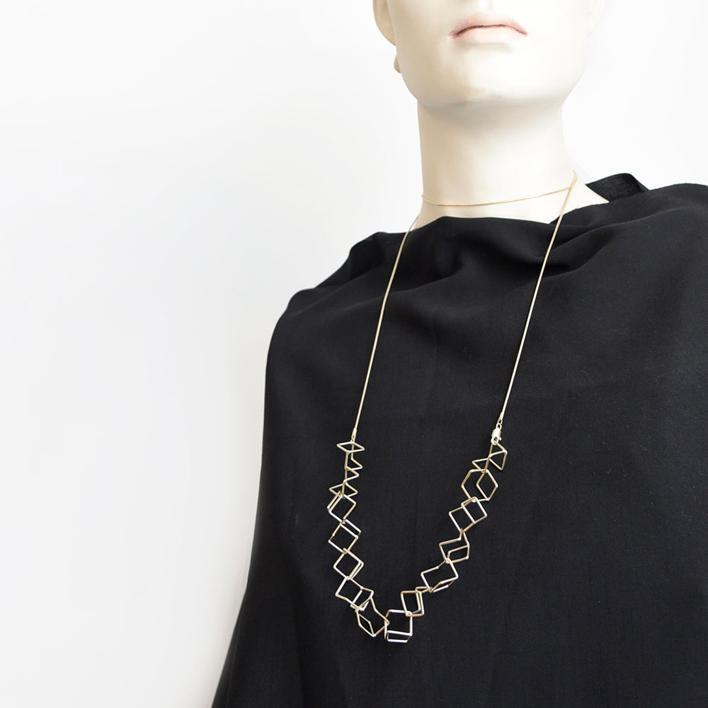 Styled view of long gold necklace on black fabric.