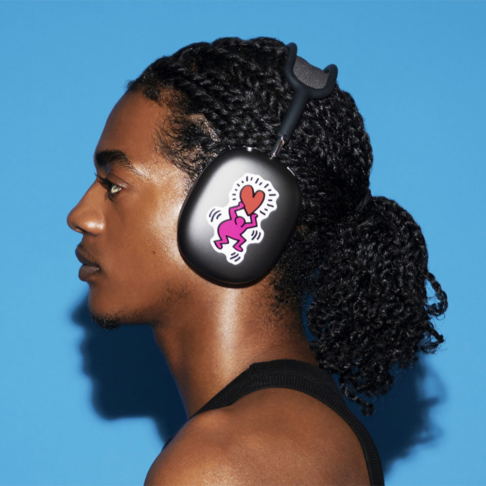 Model wearing over-ear headphones with a Keith Haring &#39;Love&#39; sticker on the left headphone.