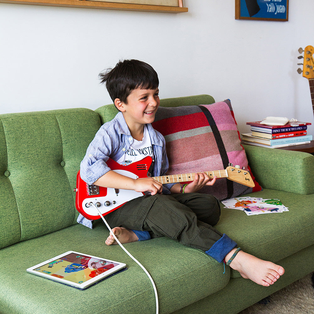 Kid model playing with guitar on couch.
