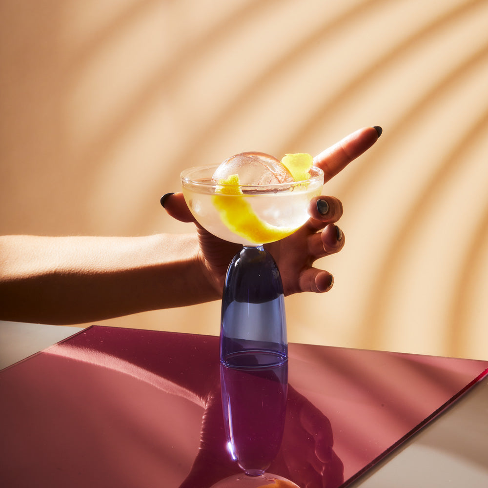Close-up model holding cocktail coupe glass.