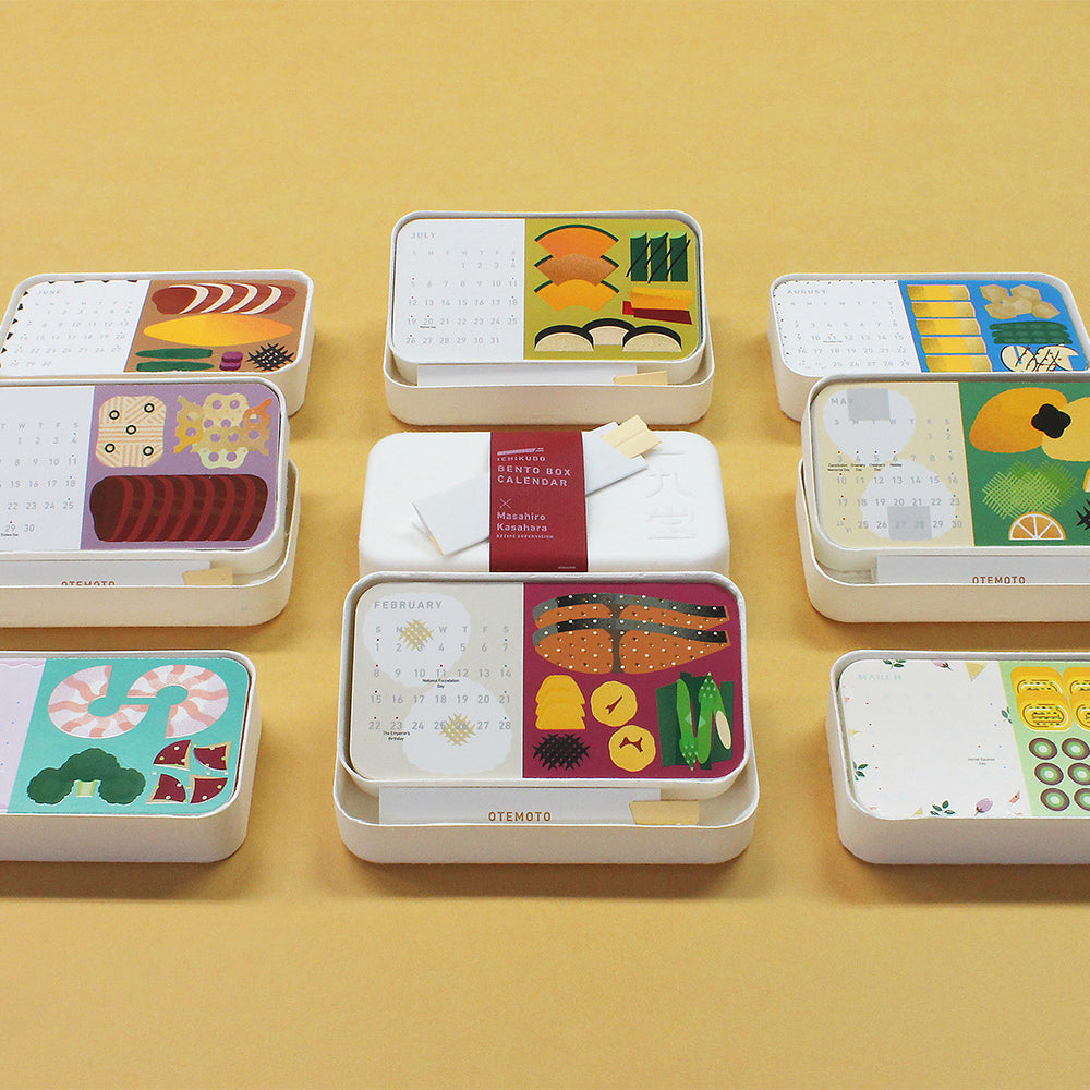 Set of small, bento boxes with monthly cards on a yellow background