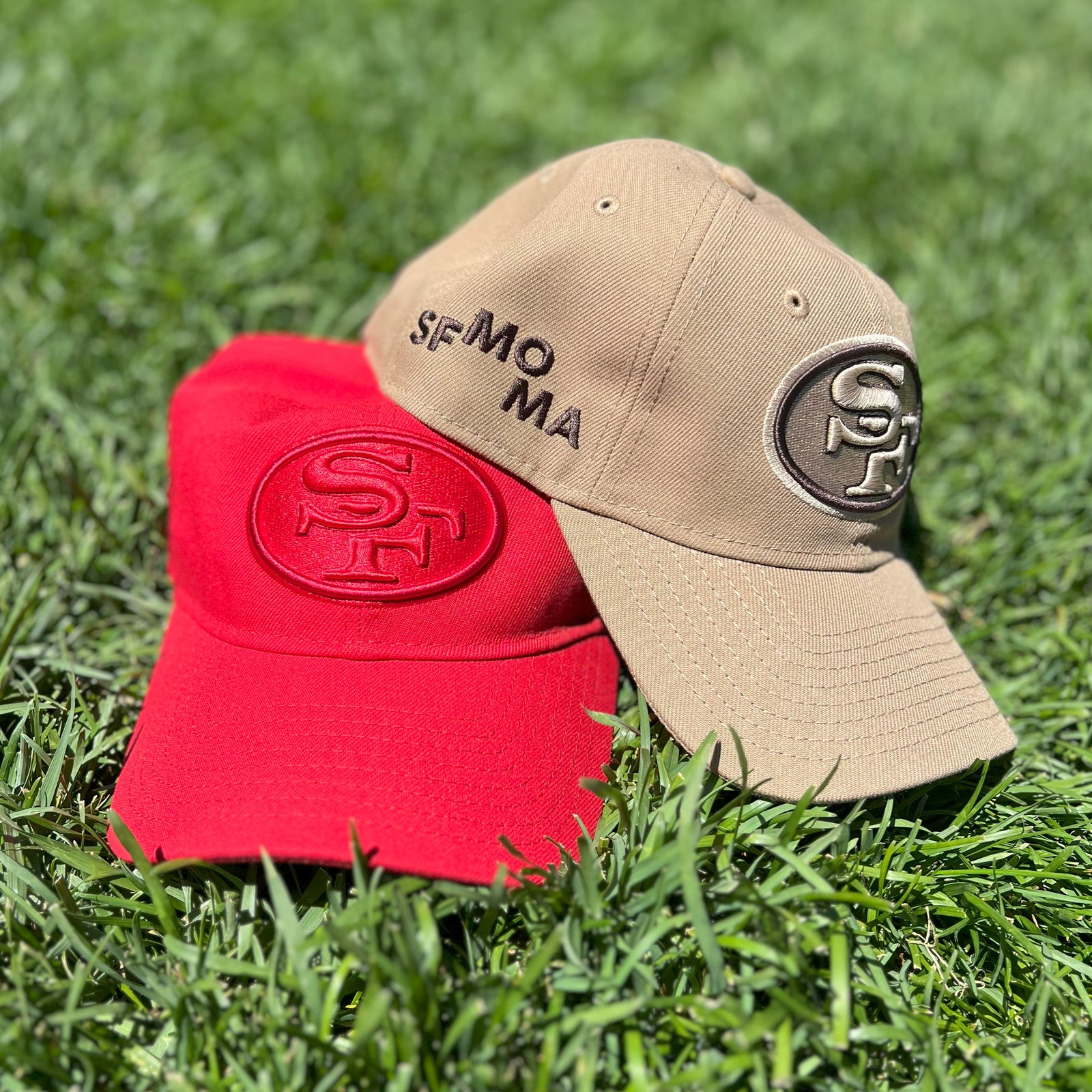 both SFMOMA x New Era San Francisco 49ers Adjustable Hats shown together on the grass