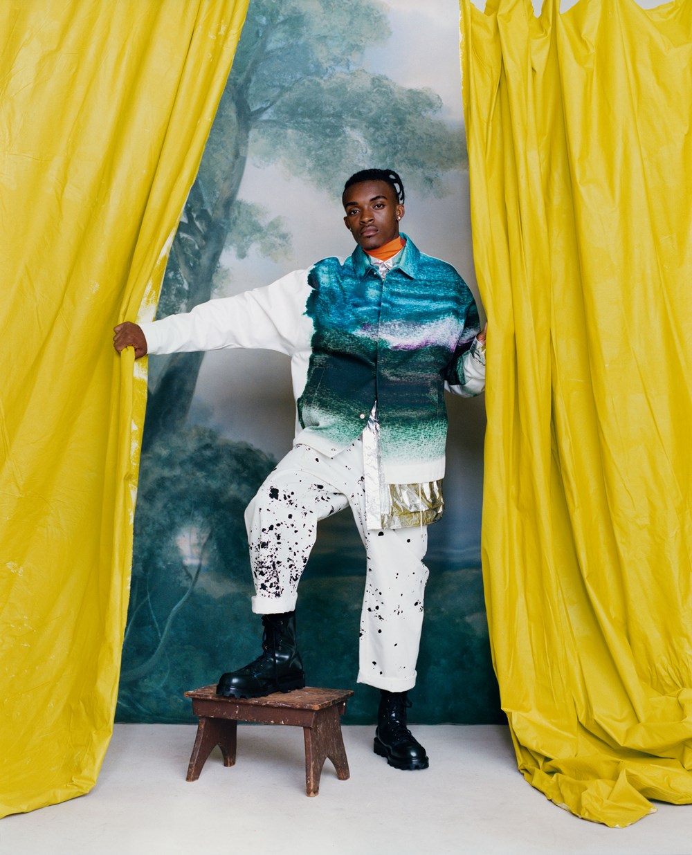 Person in colorful outfit standing between yellow curtains with a blurred natural background