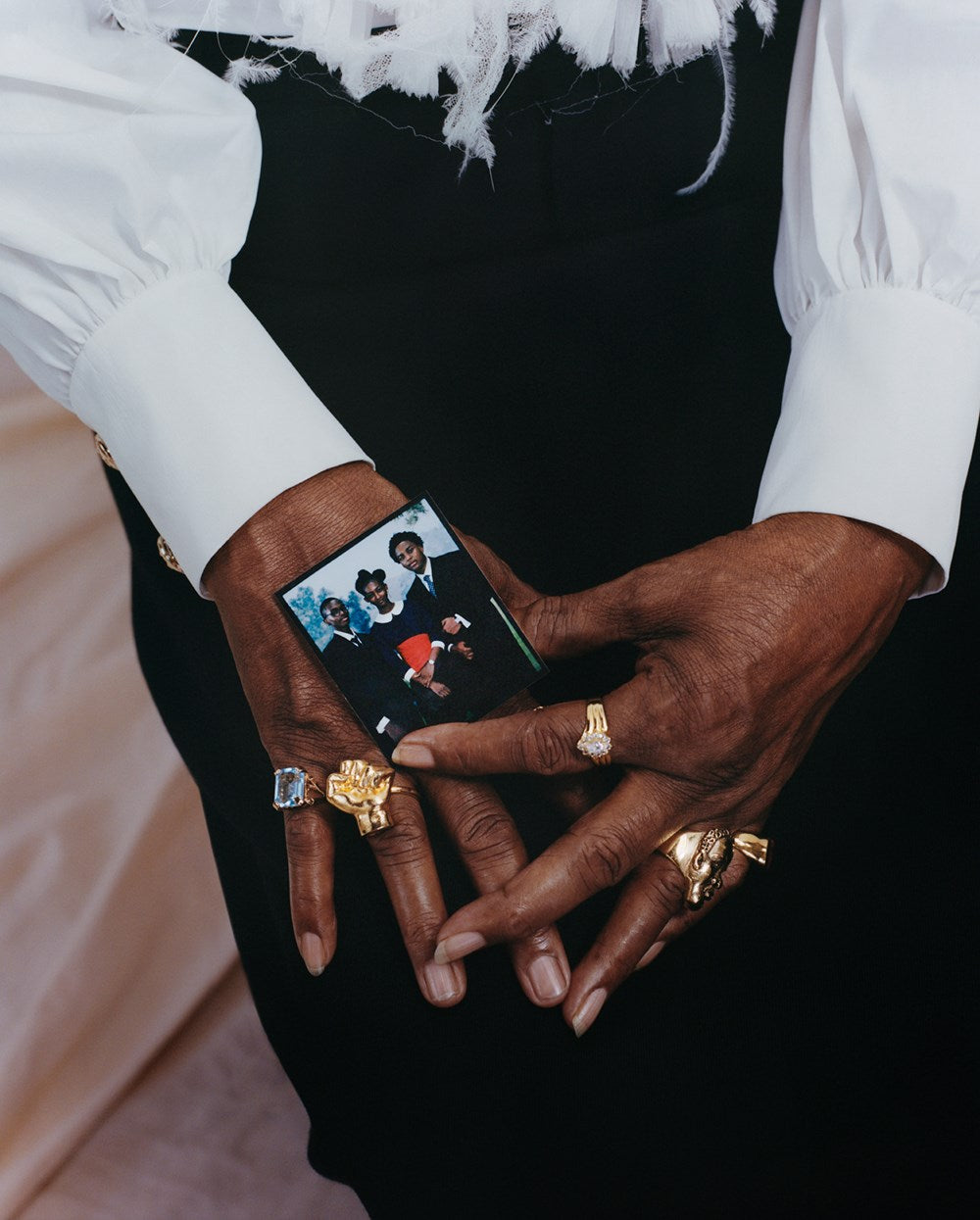 Person holding a small photo wearing gold jewelry.