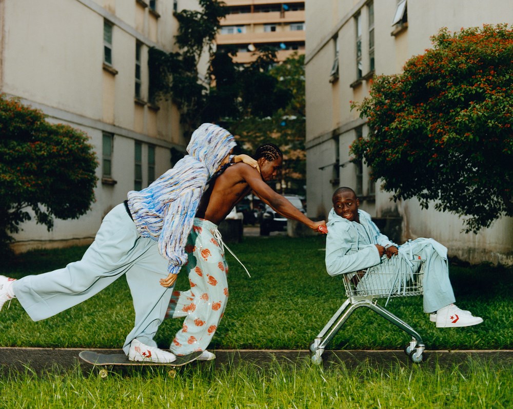 Three people in light-colored outfits interacting with a shopping cart