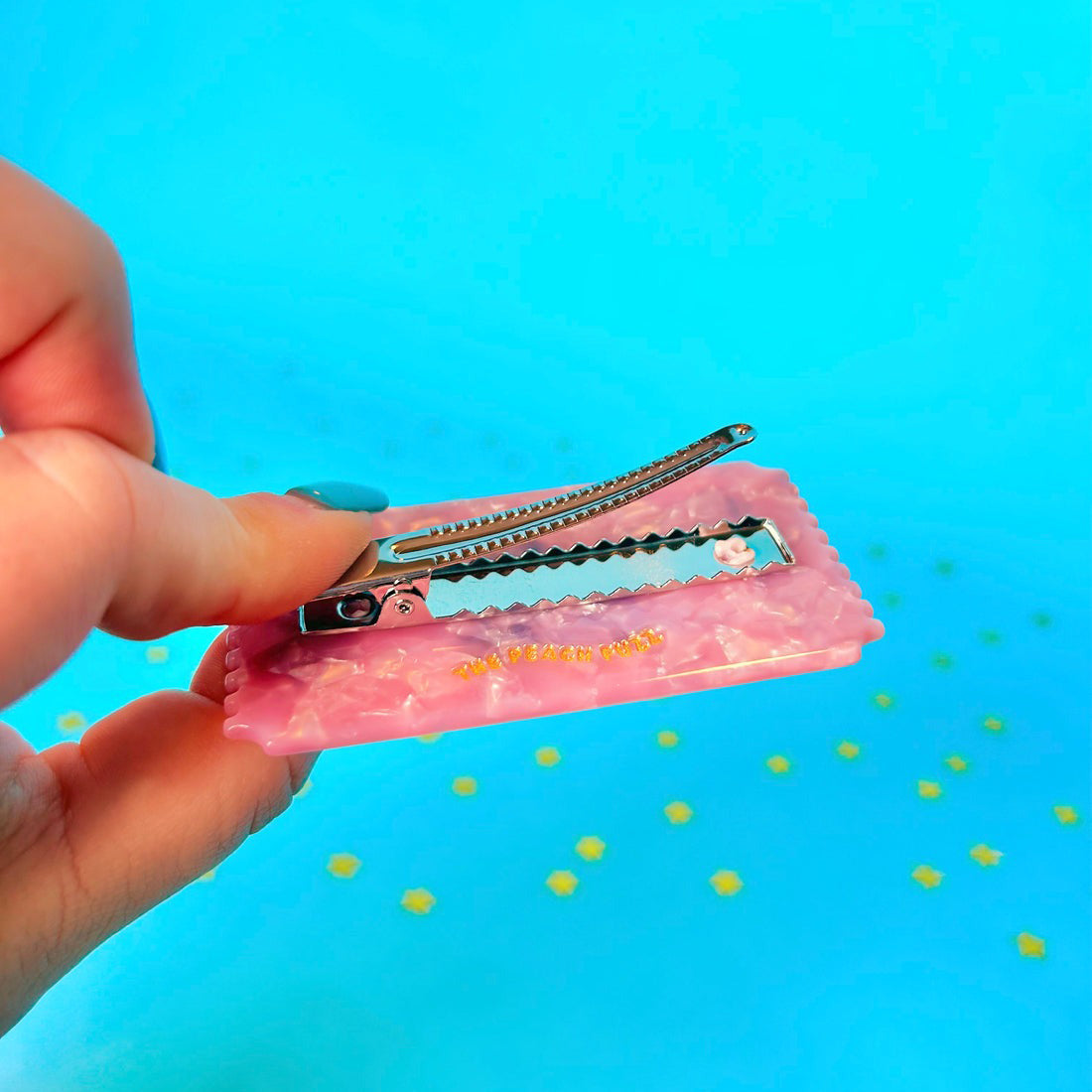 Hand holding a hair clip with a blue background