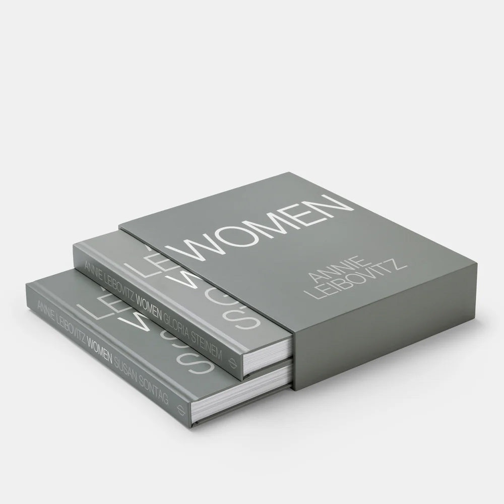 Two gray books titled 'Women' by Annie Leibovitz on a white background