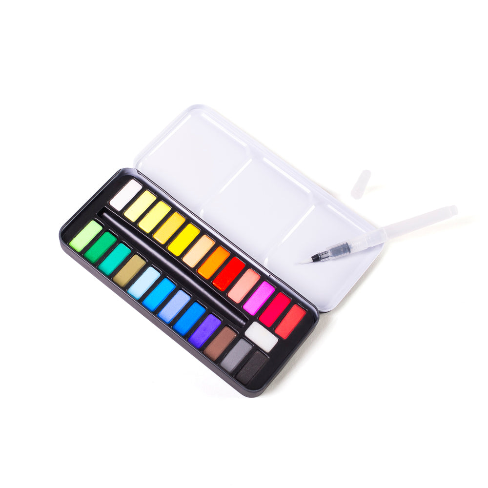 A portable watercolor paint palette with a clear plastic lid, containing 18 color pans in a spectrum of bright hues, and a small clear brush with a black tip resting inside the lid, shown on a solid white background.