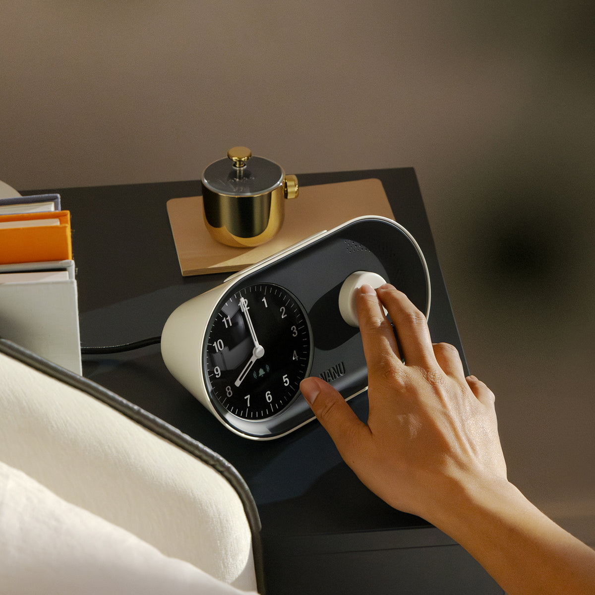 Person adjusting a modern alarm clock on a bedside table.