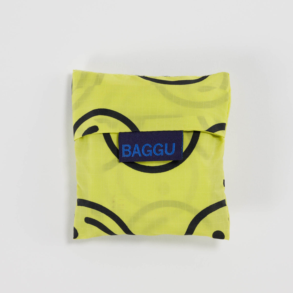 Yellow reusable bag with black patterns and a blue 'BAGGU' logo on a light gray background