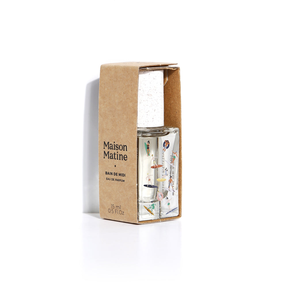 Maison Matine Bain de Midi Eau de Parfum in a clear glass bottle with colorful illustrations, displayed next to its brown kraft paper packaging box on a white background.