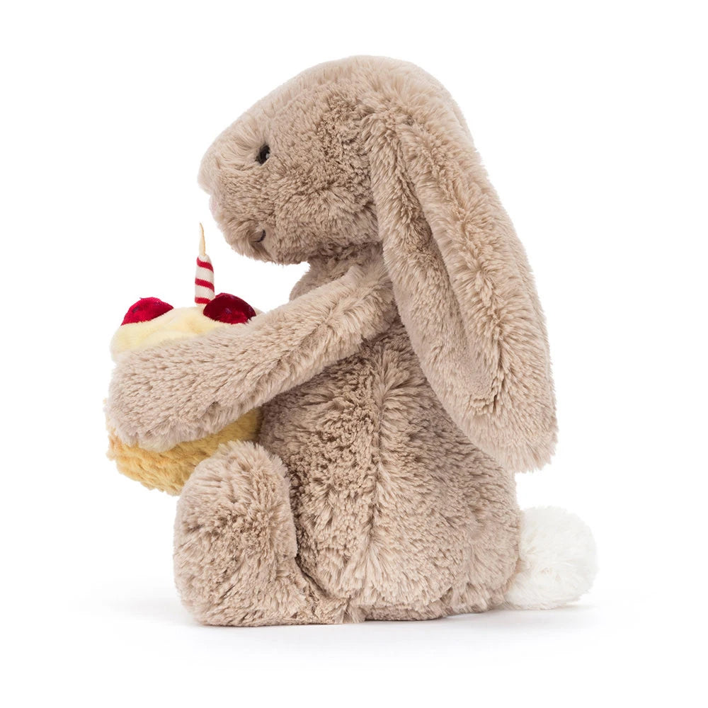Plush bunny holding a small cake with a candle on a white background