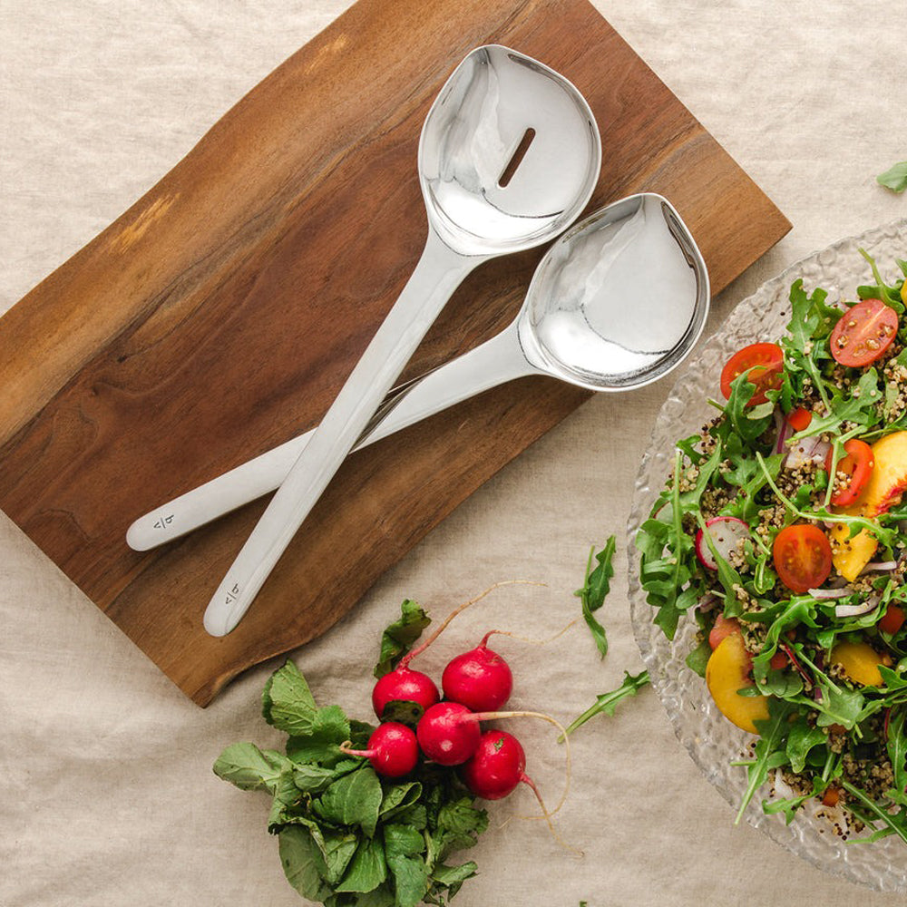 Spoons on wooden board next to salad.