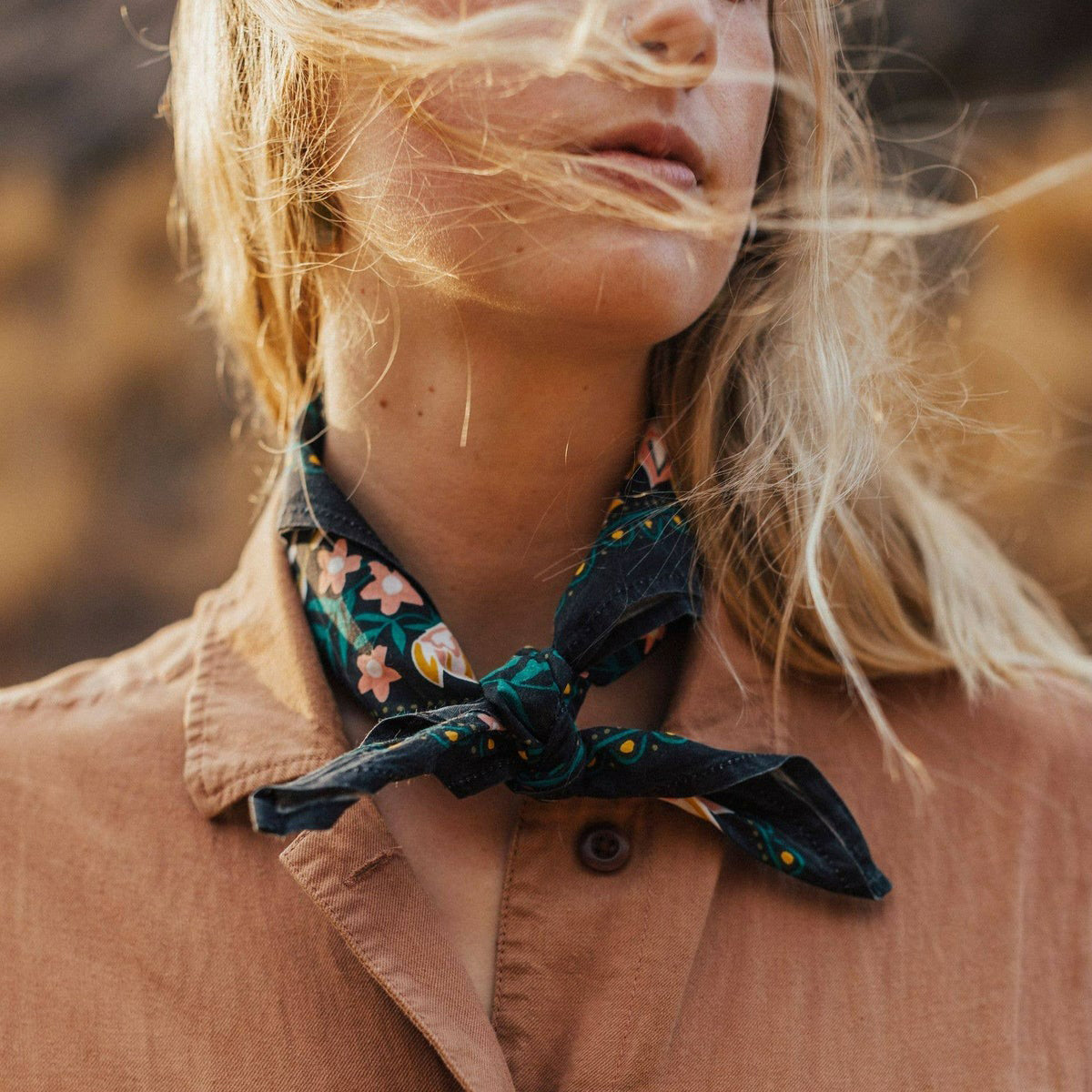 Close-up of a person wearing a floral scarf with a blurred natural background