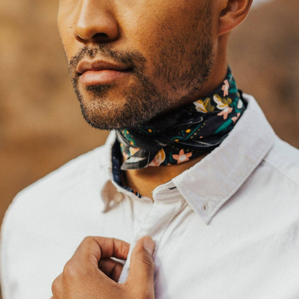 Man wearing a floral-patterned neck scarf with a blurred background