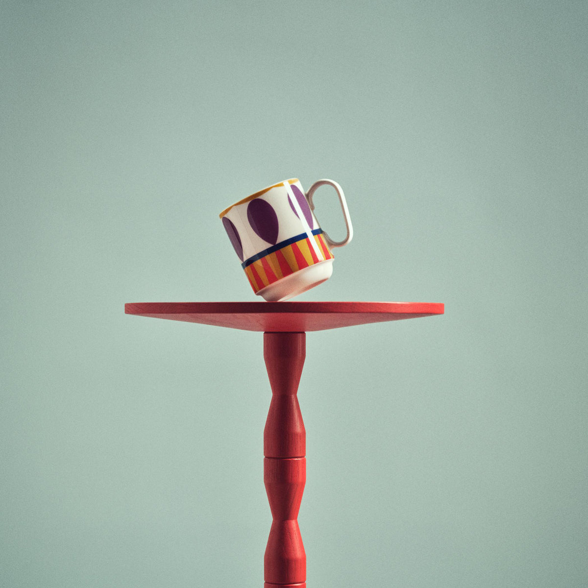 Colorful abstract mug on red table.