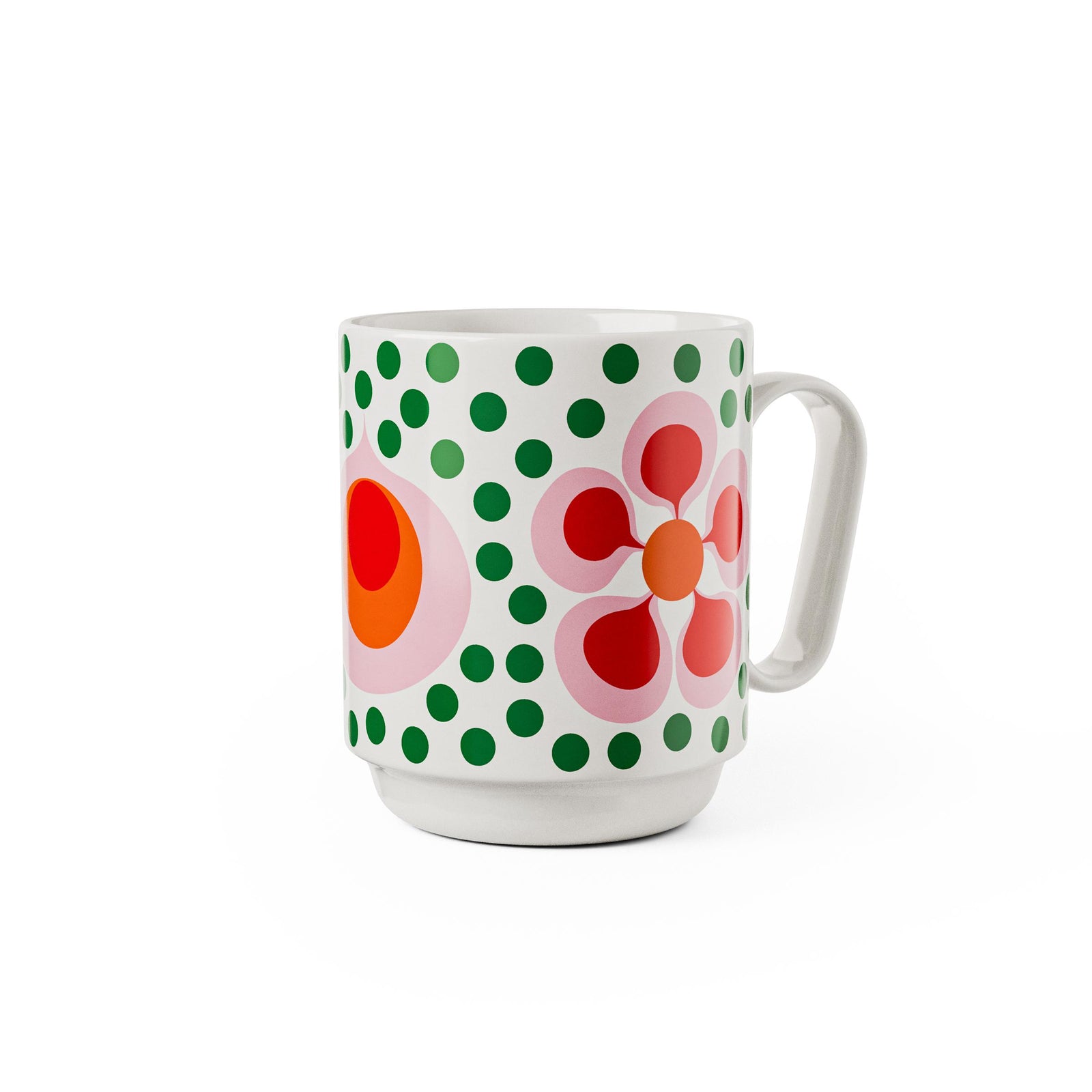 A white ceramic coffee mug featuring a retro mid-century modern design with green polka dots, a pink flower, and concentric red and orange circles, shown on a plain white background.