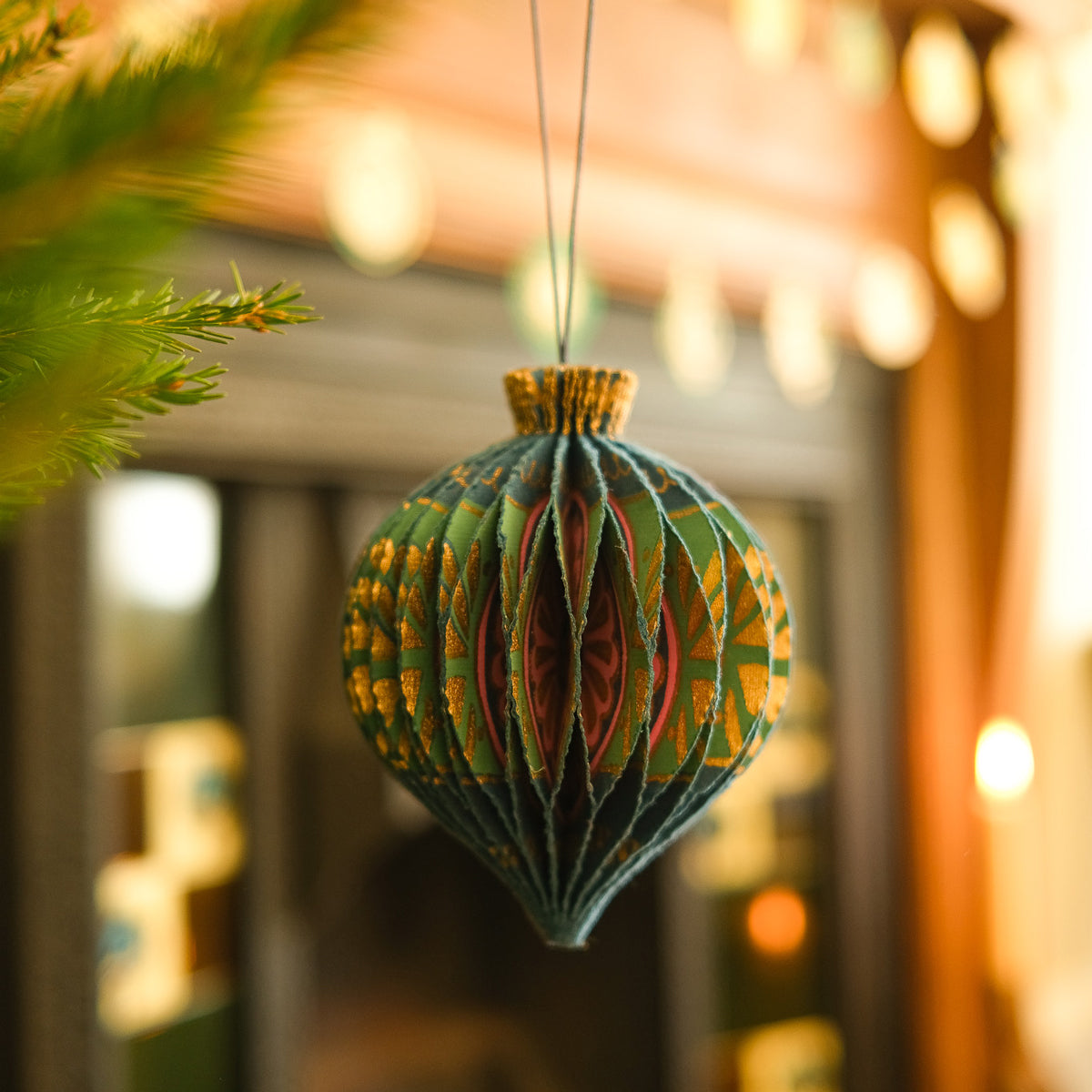 Decorative Christmas ornament hanging on a tree with blurred lights in the background