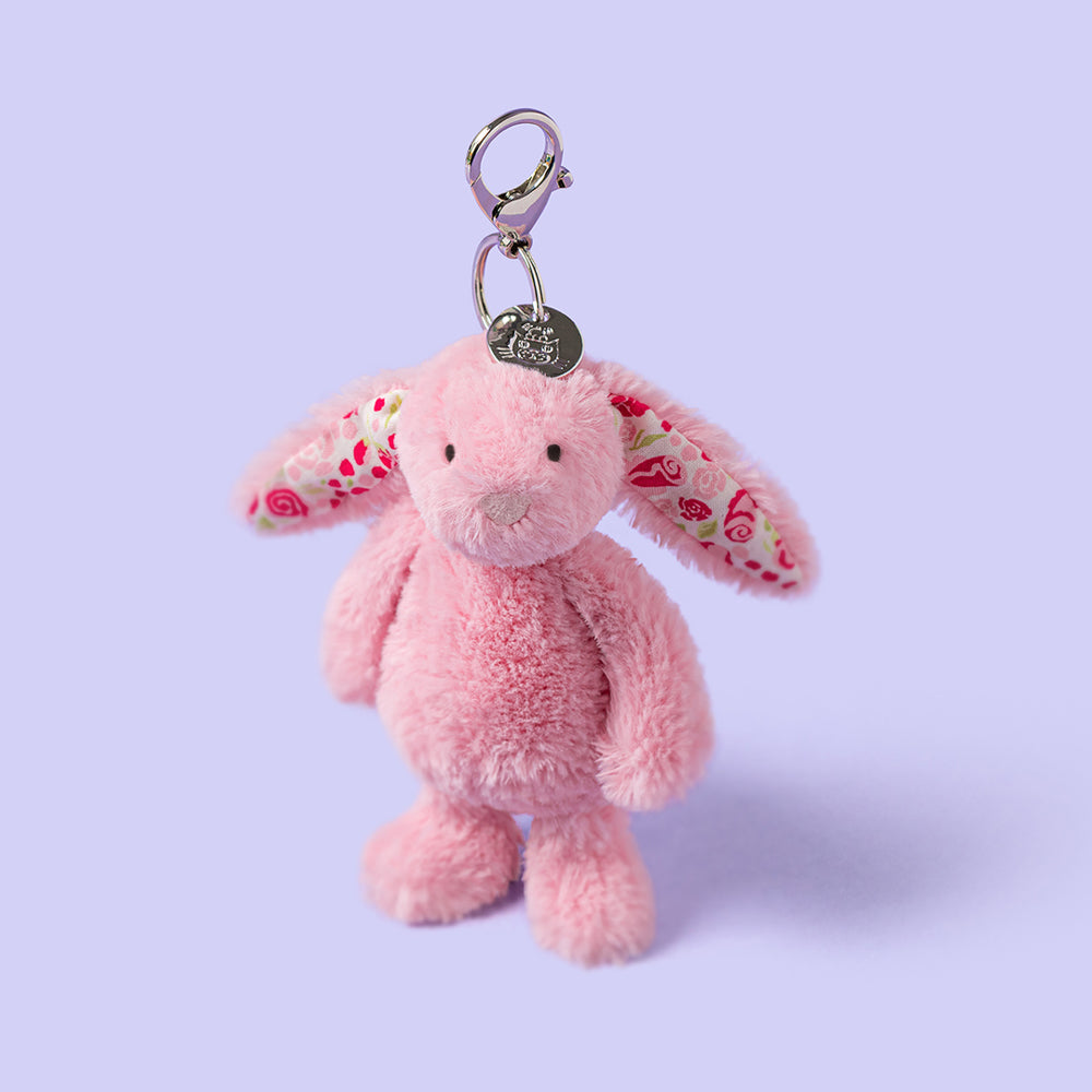 Pink plush bunny keychain with floral ears on a light purple background