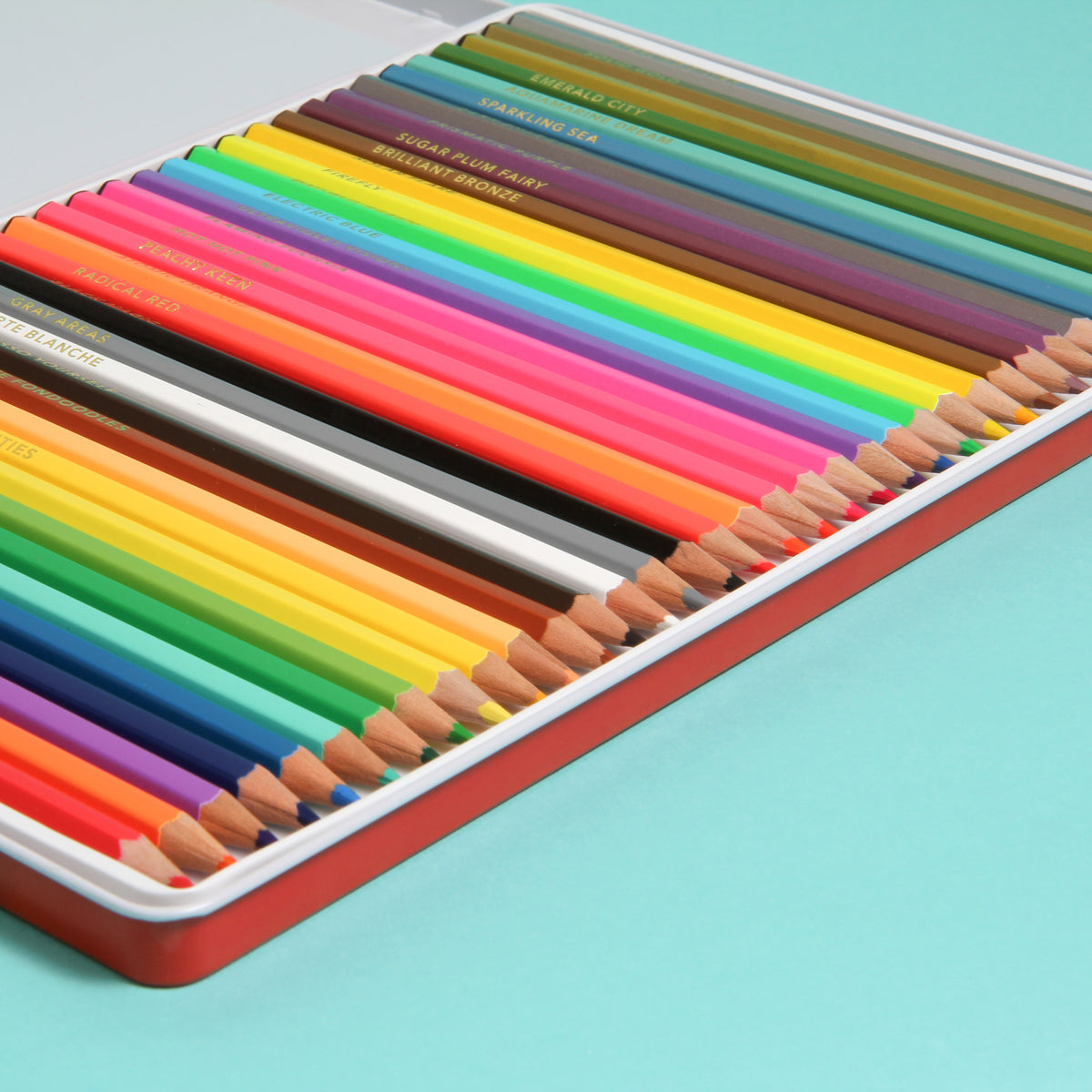 Set of colorful pencils in a metal case on a light blue background