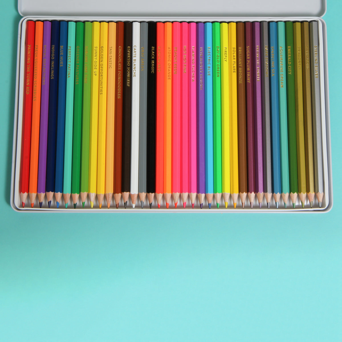 Set of colored pencils in a metal box on a turquoise background