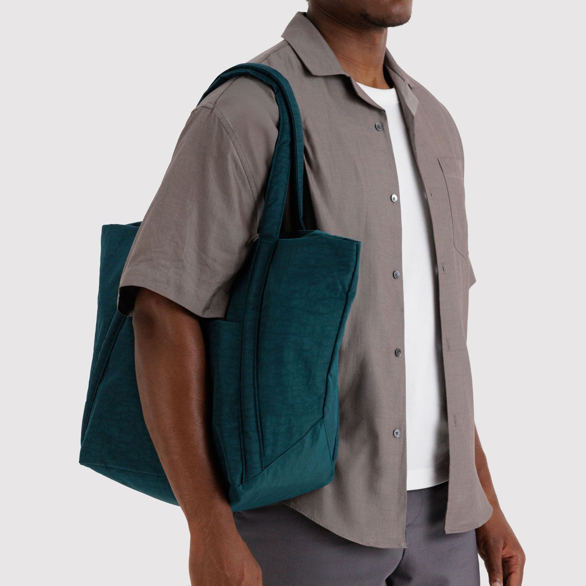 Man carrying a teal tote bag on a plain background