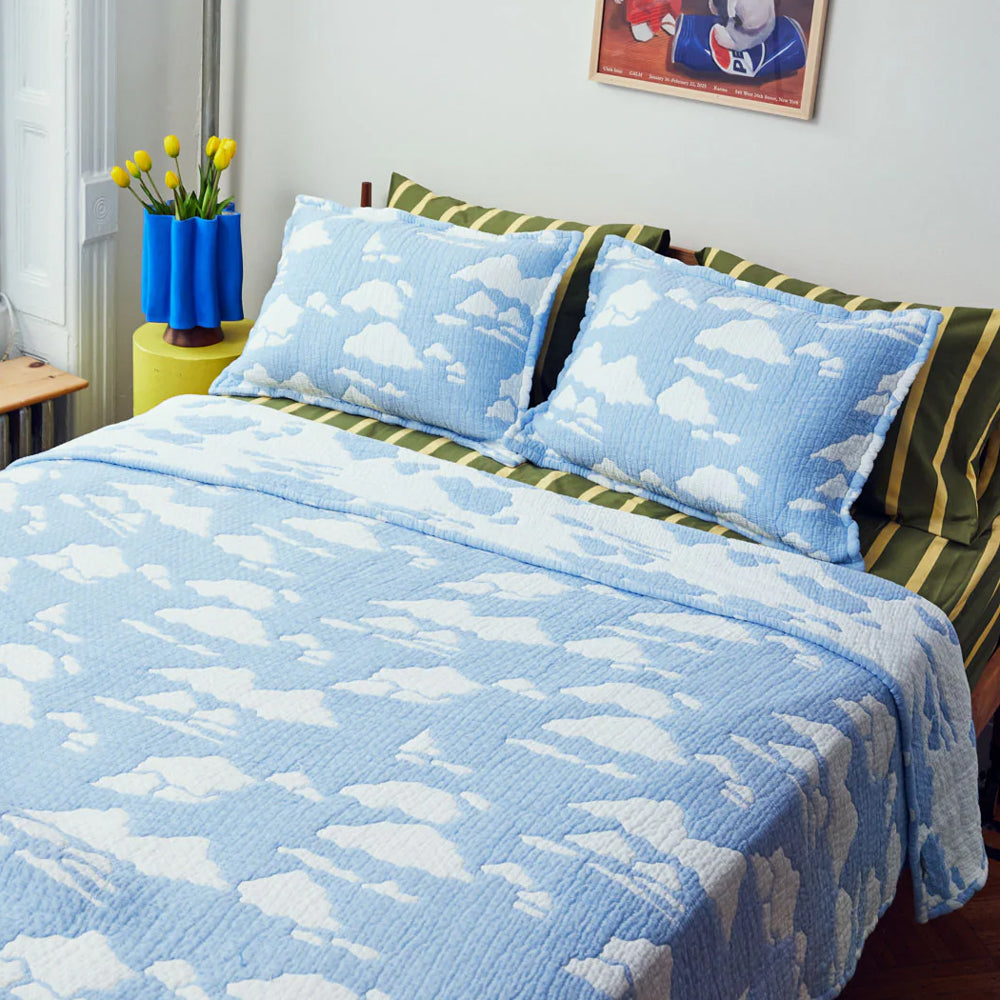 Bed with blue cloud-patterned bedding and pillows in a room setting.