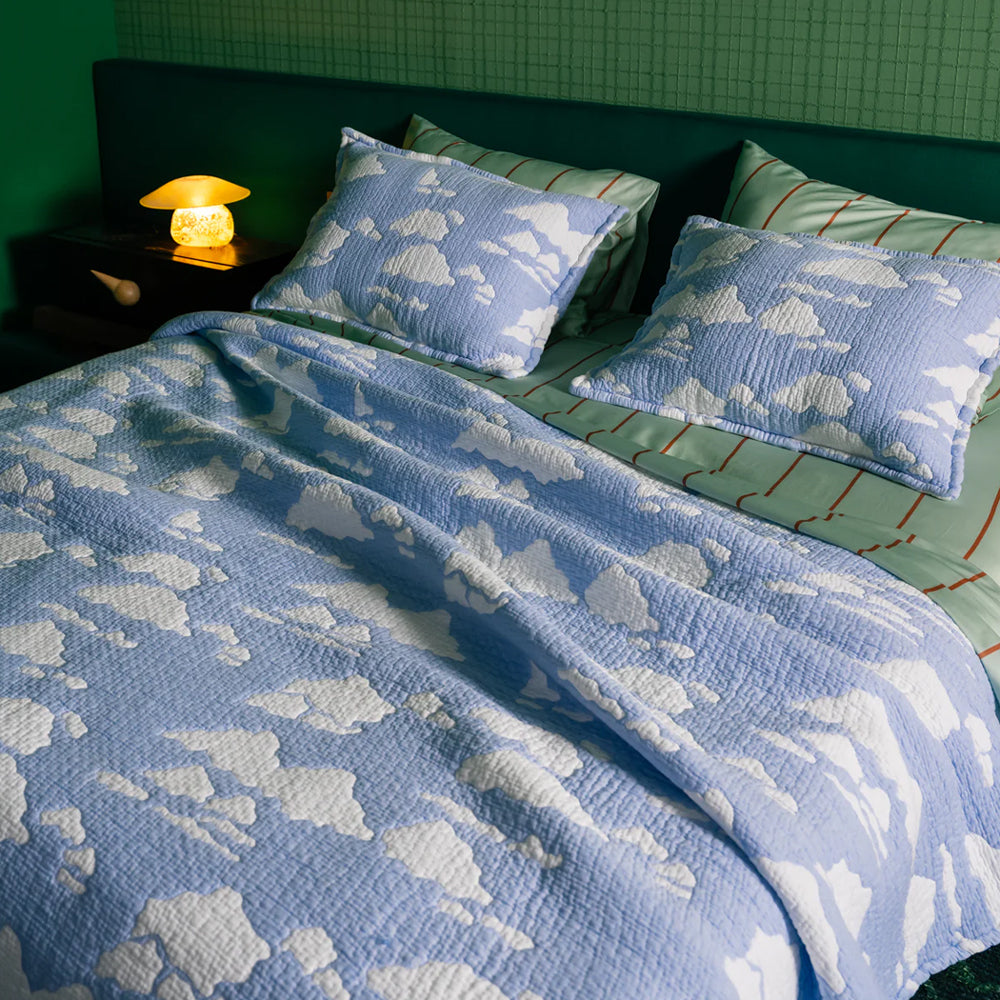 Bed with blue cloud-patterned bedding and pillows in a room setting.