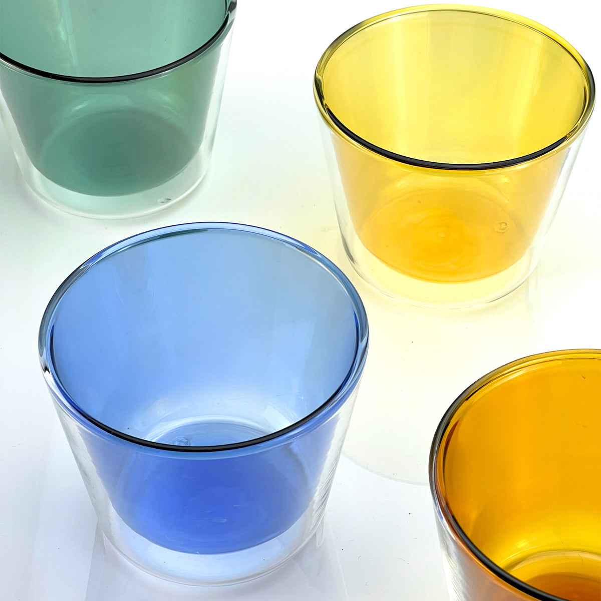 Four colored glass tumblers on a white background