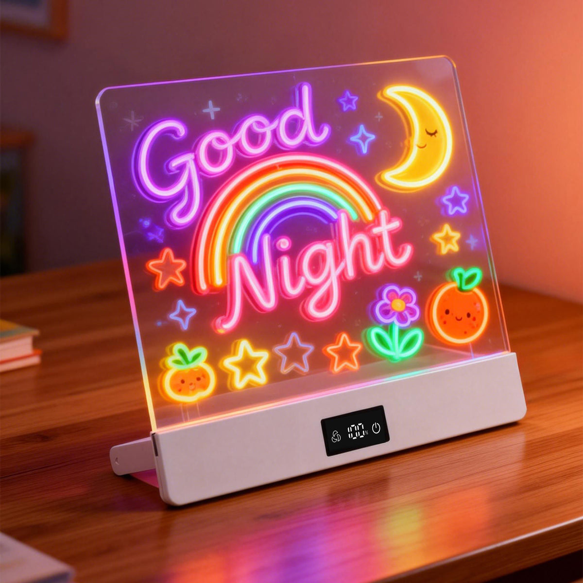 A glowing LED acrylic desk lamp with a white base, displaying a colorful 'Good Night' neon-style design with a rainbow, moon, stars, flowers, and fruit on a wooden table.