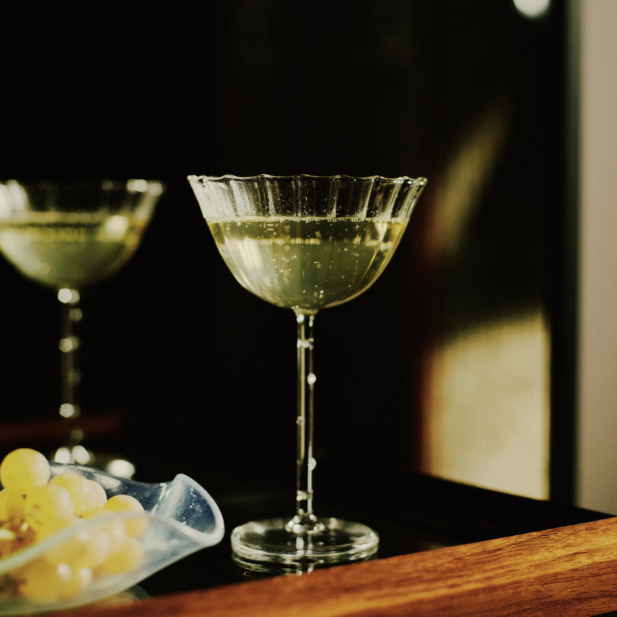 Cocktail in a decorative glass with grapes on a wooden surface