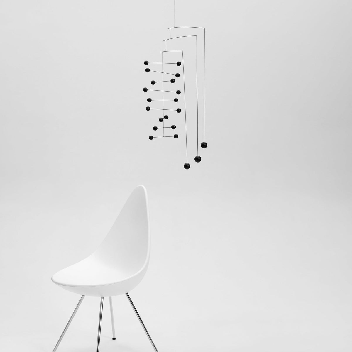 Modern white chair with mobile on a light gray background