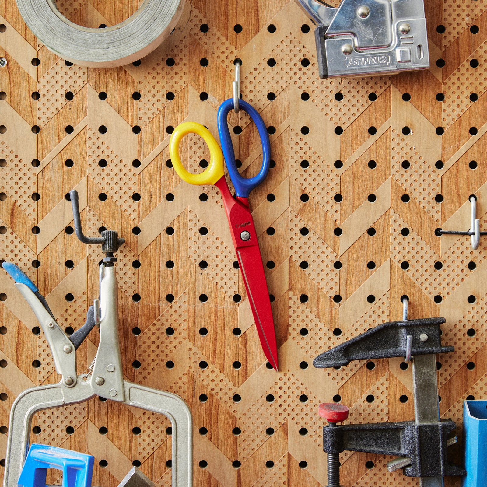 Colorful scissors with red handle, yellow pivot, and blue blades on a white background