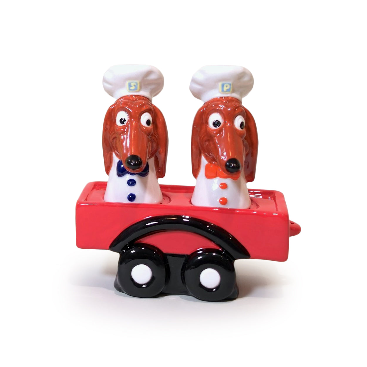 Two dog-shaped salt and pepper shakers with a red cart on a white background