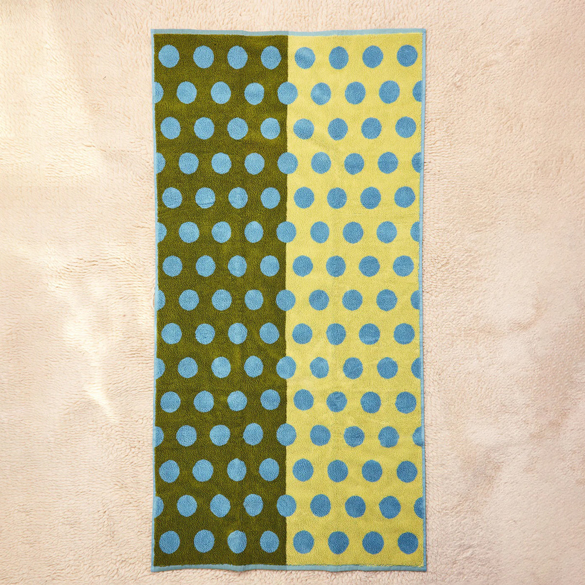 Towel with green and yellow polka dot pattern on a beige background