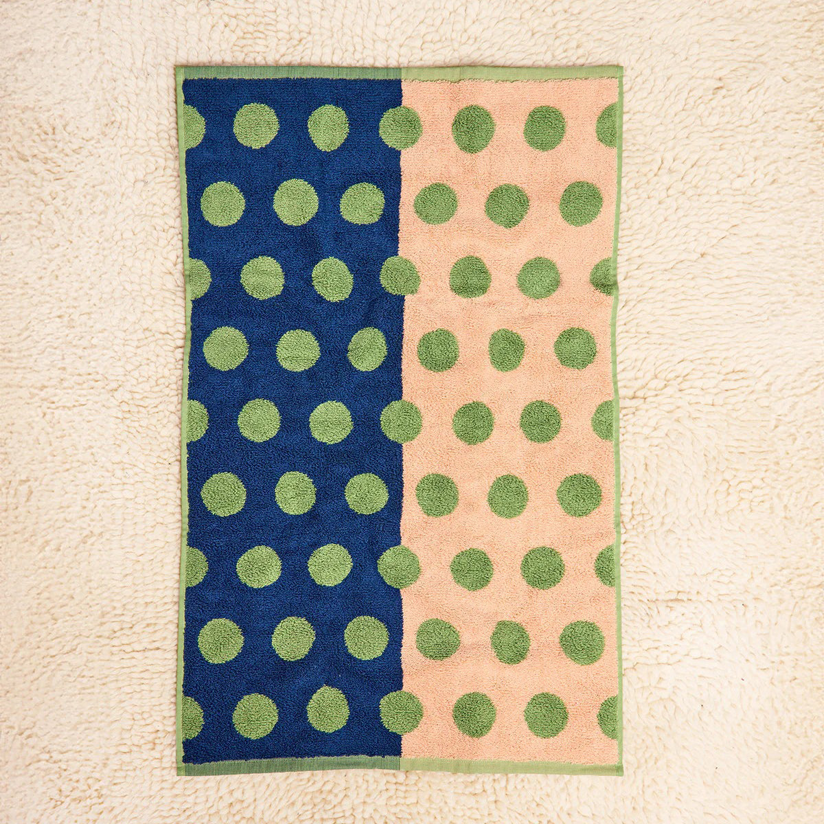 Towel with green polka dots on a blue and pink background
