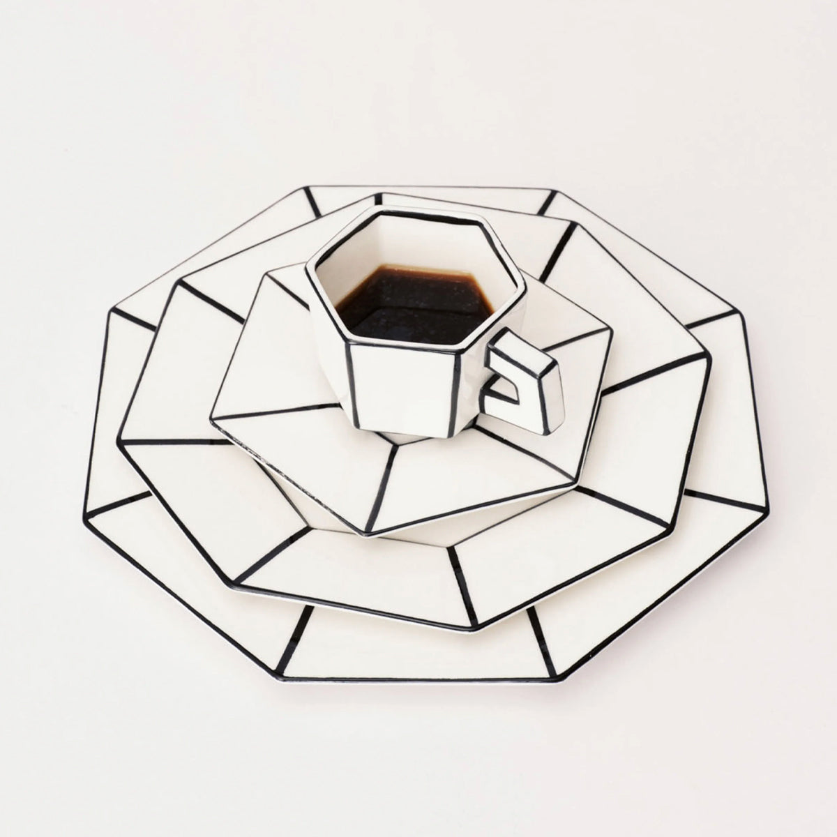 Geometrically shaped white plate with a cup of coffee on a light gray background