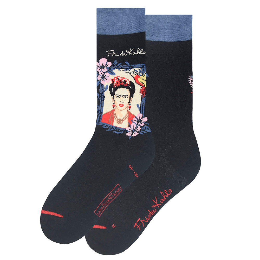 A pair of black crew socks featuring a graphic print of Frida Kahlo's portrait with flowers and her signature on the side, set against a plain white background.