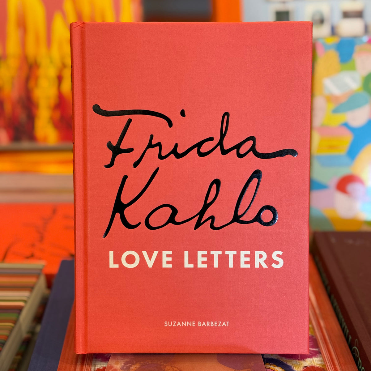 Book titled 'Frida Kahlo Love Letters' with a red cover and black text, placed on a colorful surface.