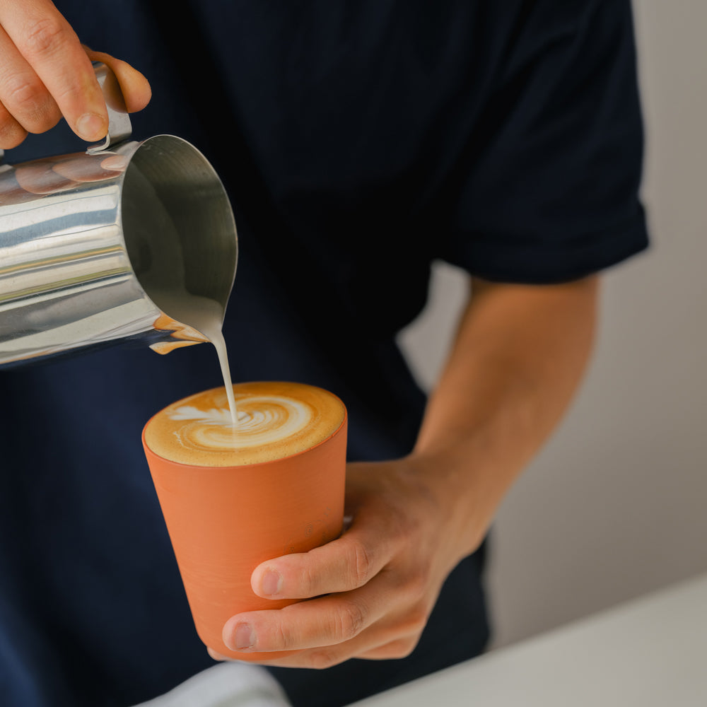 Model pouring creamer in cup.