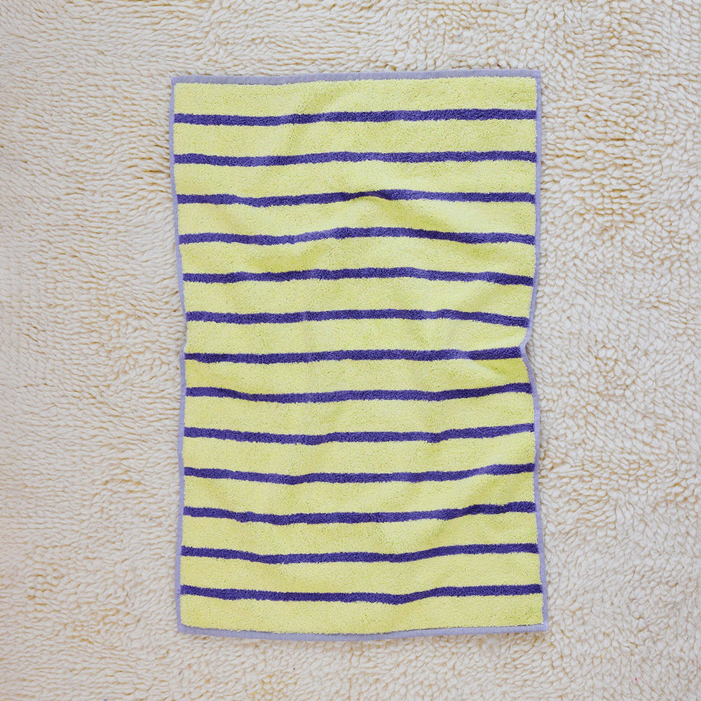 Striped yellow and purple towel on a textured beige surface