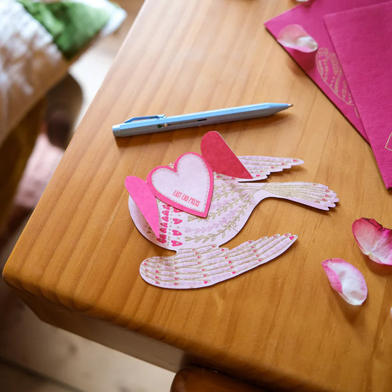 Paper bird with heart on a wooden surface