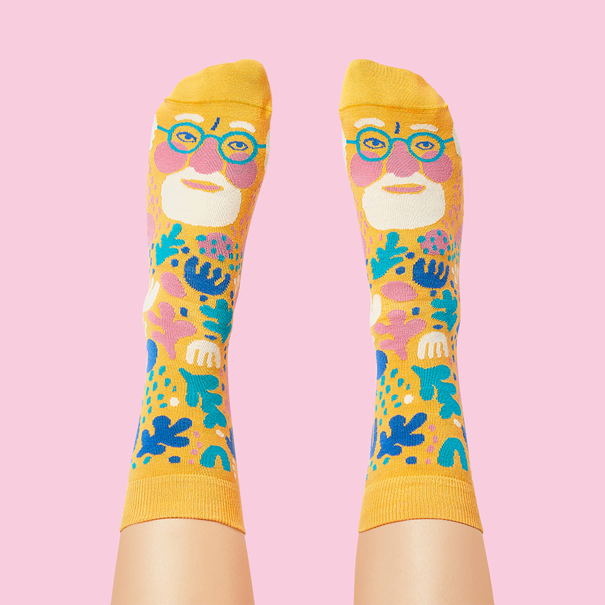 Colorful socks with a face design on a pink background