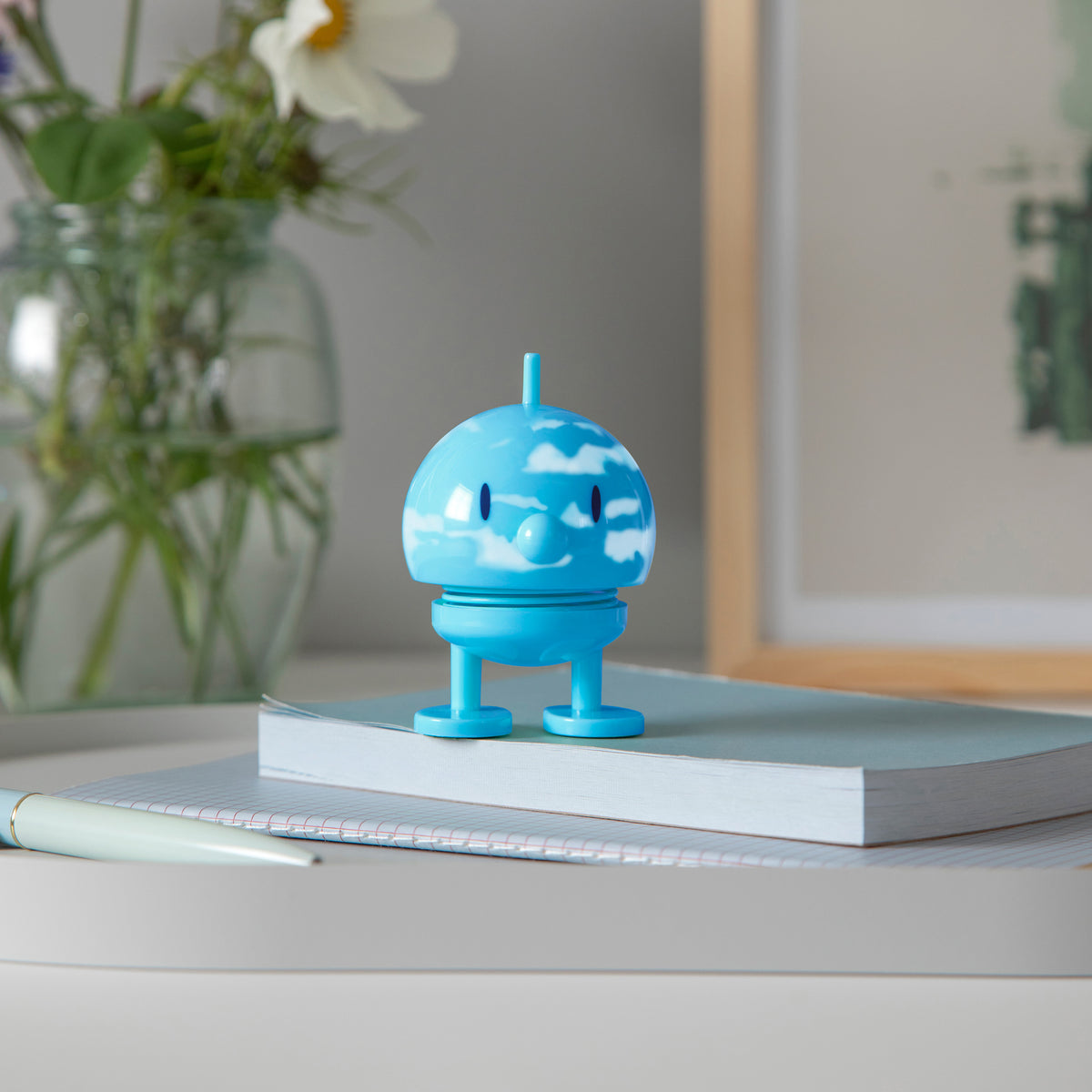 Blue cloud-Hoptimist on a notebook with a pen and flowers in the background