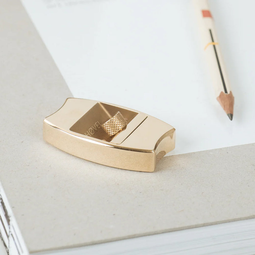 Gold sharpener on a white surface with a pen in the background