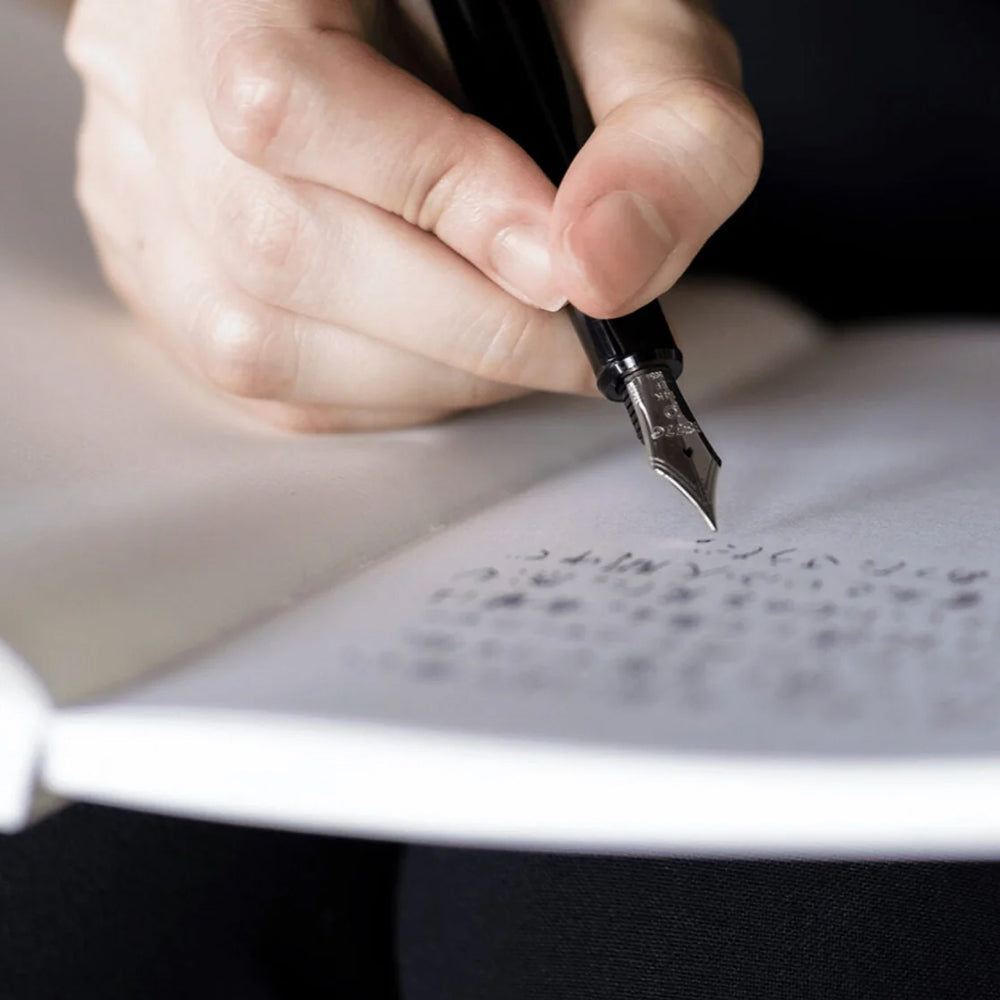Hand holding a fountain pen writing on paper