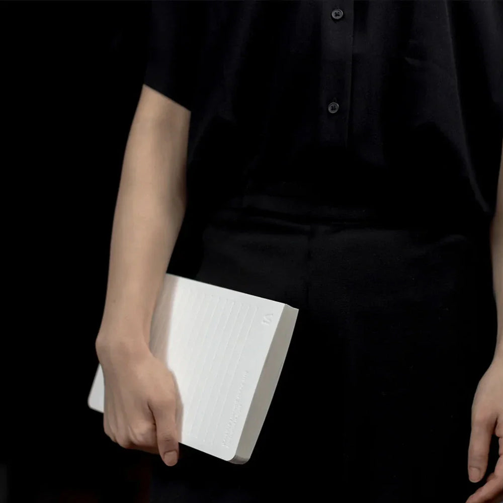 Person holding a white book against a black background